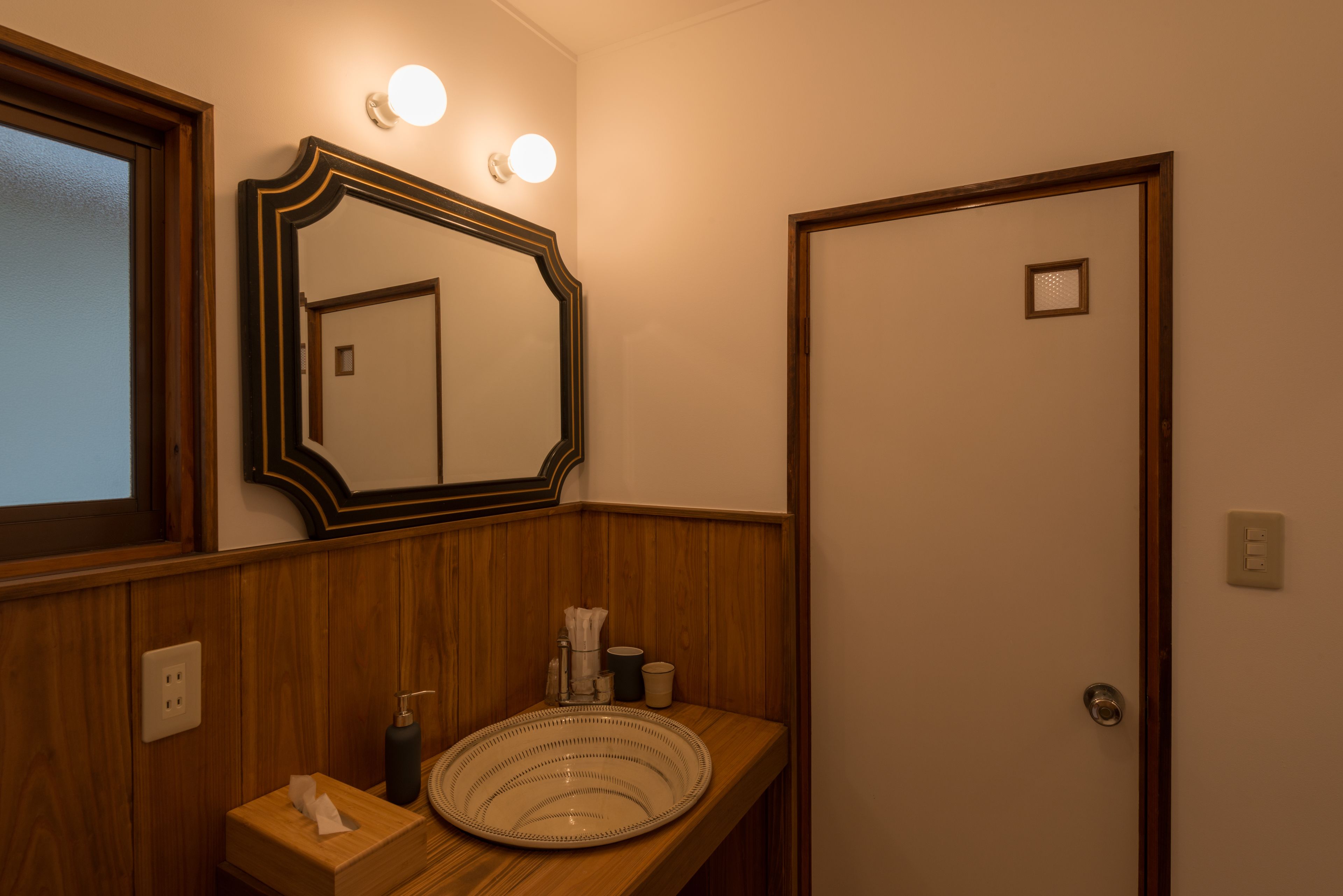 Un baño con tocador de madera, un espejo grande y una puerta.