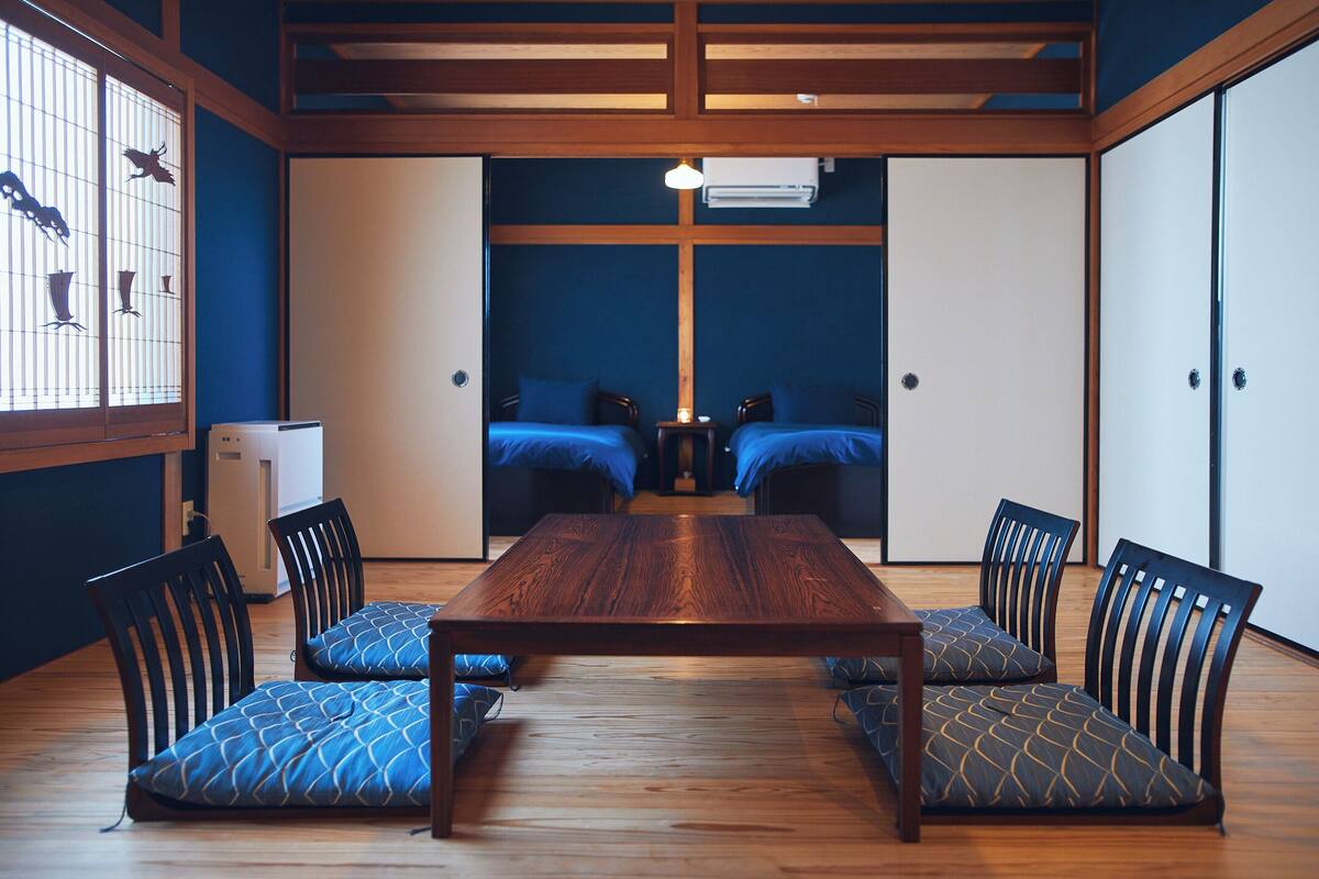 A traditional Japanese-style room with a wooden table, blue patterned cushions, and sliding doors.