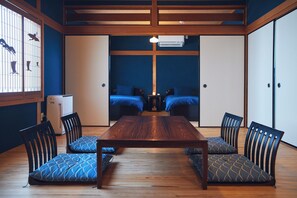 Una habitación tradicional japonesa con una mesa de madera, cojines de estampado azul y puertas correderas.