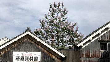 A rustic building with a signboard, wooden walls, and a tree with pink flowers.