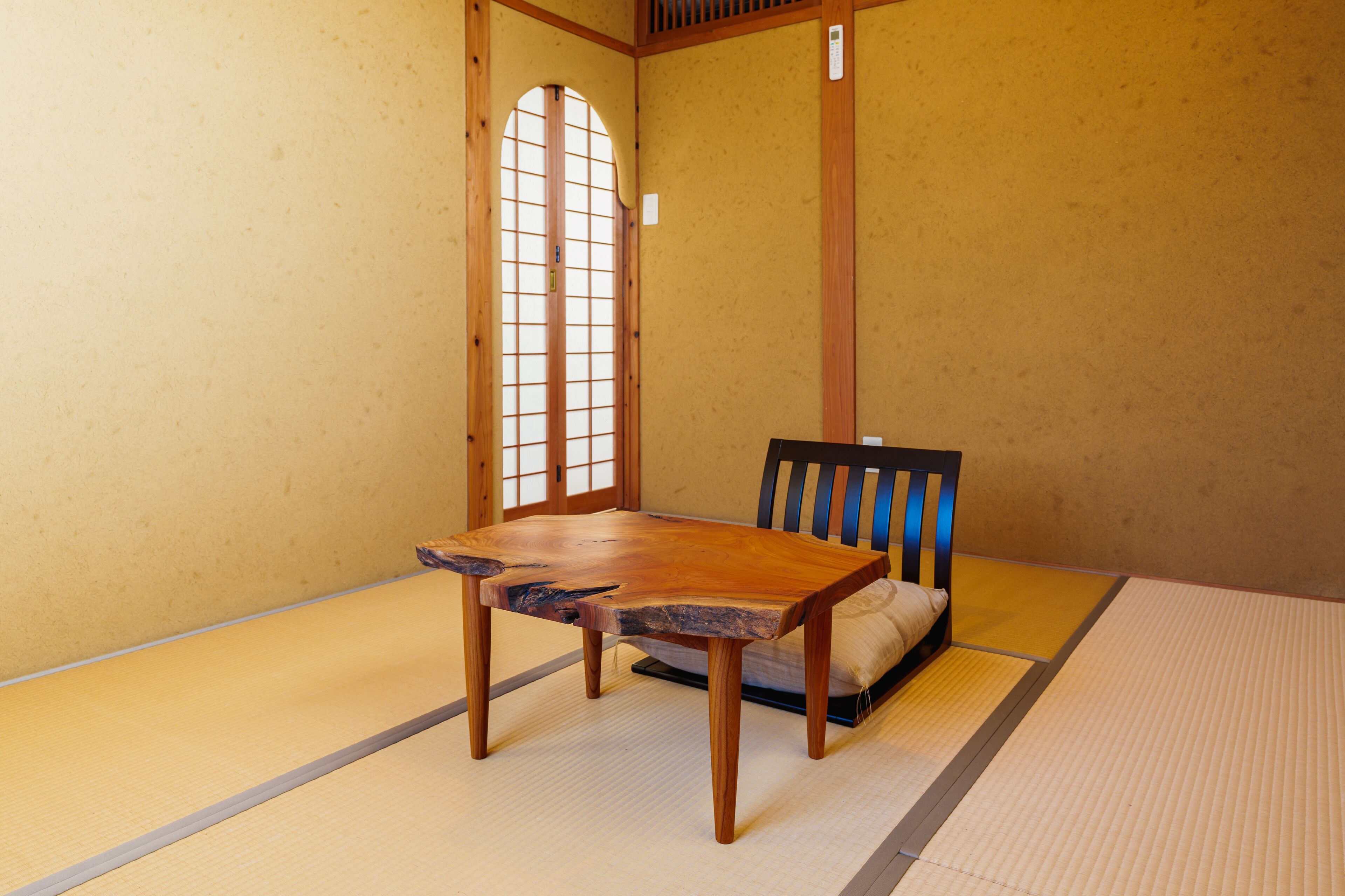 A tatami mat room with a wooden table and a chair.