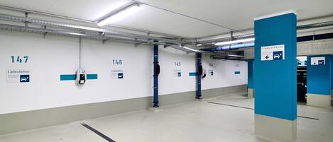 A clean, well-lit parking garage with numbered parking bays and clear signage for Ladestation.