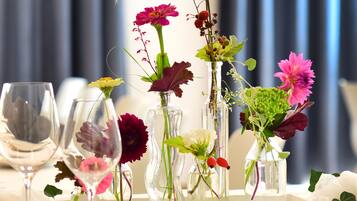 Una mesa dispuesta para comer con varios jarrones de flores y copas de vino.
