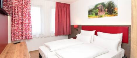 Una camera d'hotel con un letto, un comodino in legno, un quadro al muro e una finestra con tende.