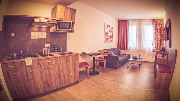 Un espacio habitable compacto con kitchenette, comedor y zona de estar.