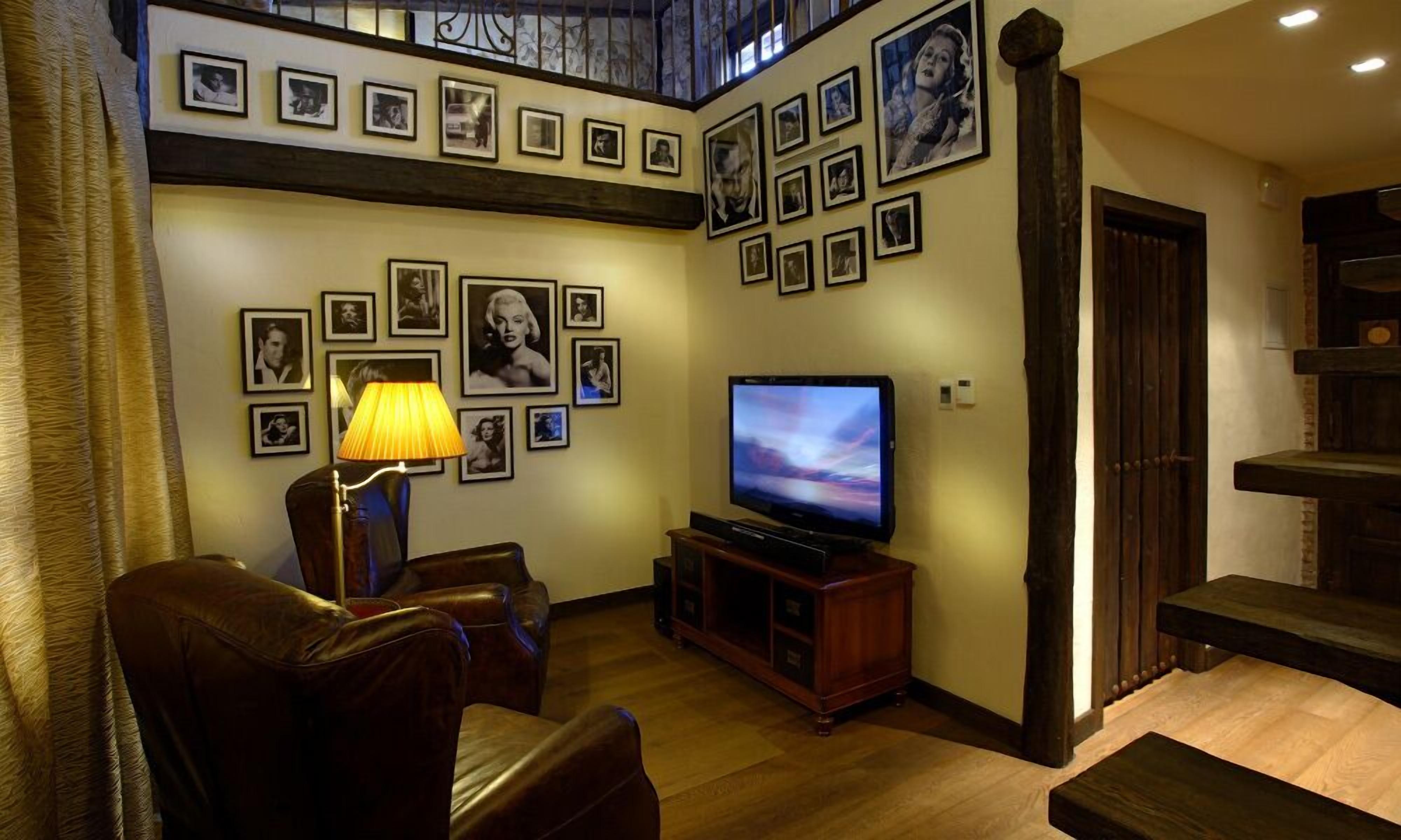Una sala de estar con televisor, sofás de cuero y una pared decorada con cuadros.