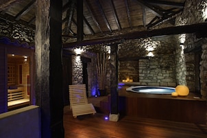 A stone-walled spa area with wooden benches and a hot tub.
