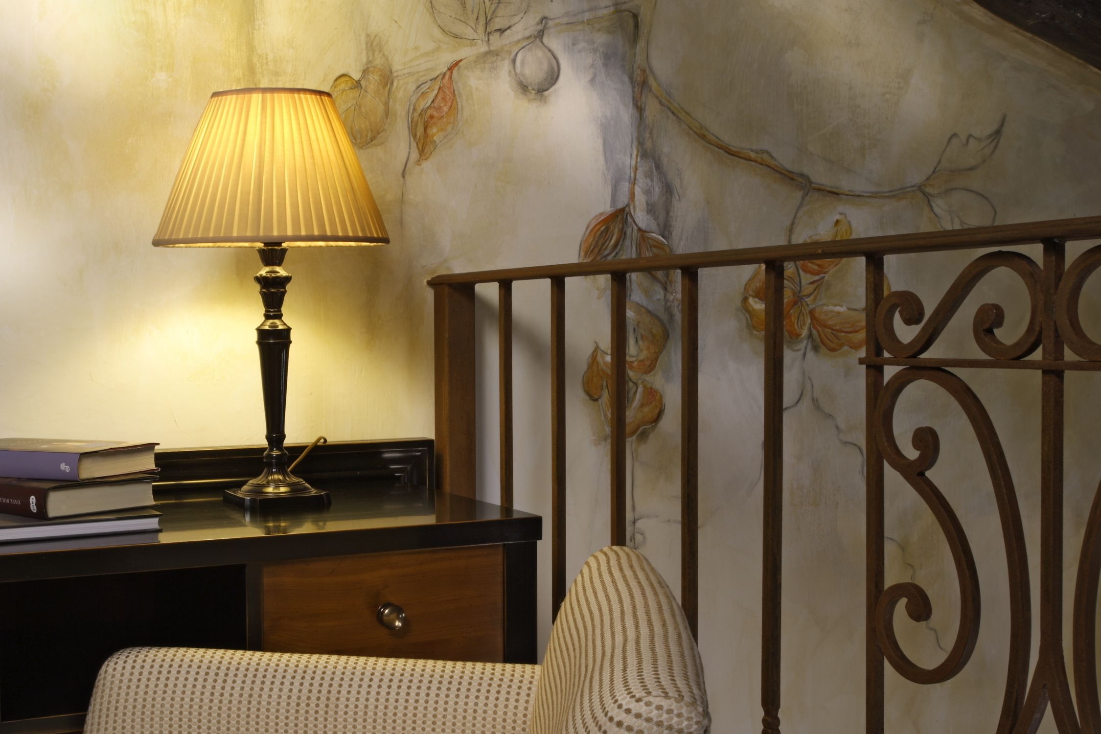 Una habitación con un escritorio, una lámpara, una silla y un detalle decorativo en la pared.