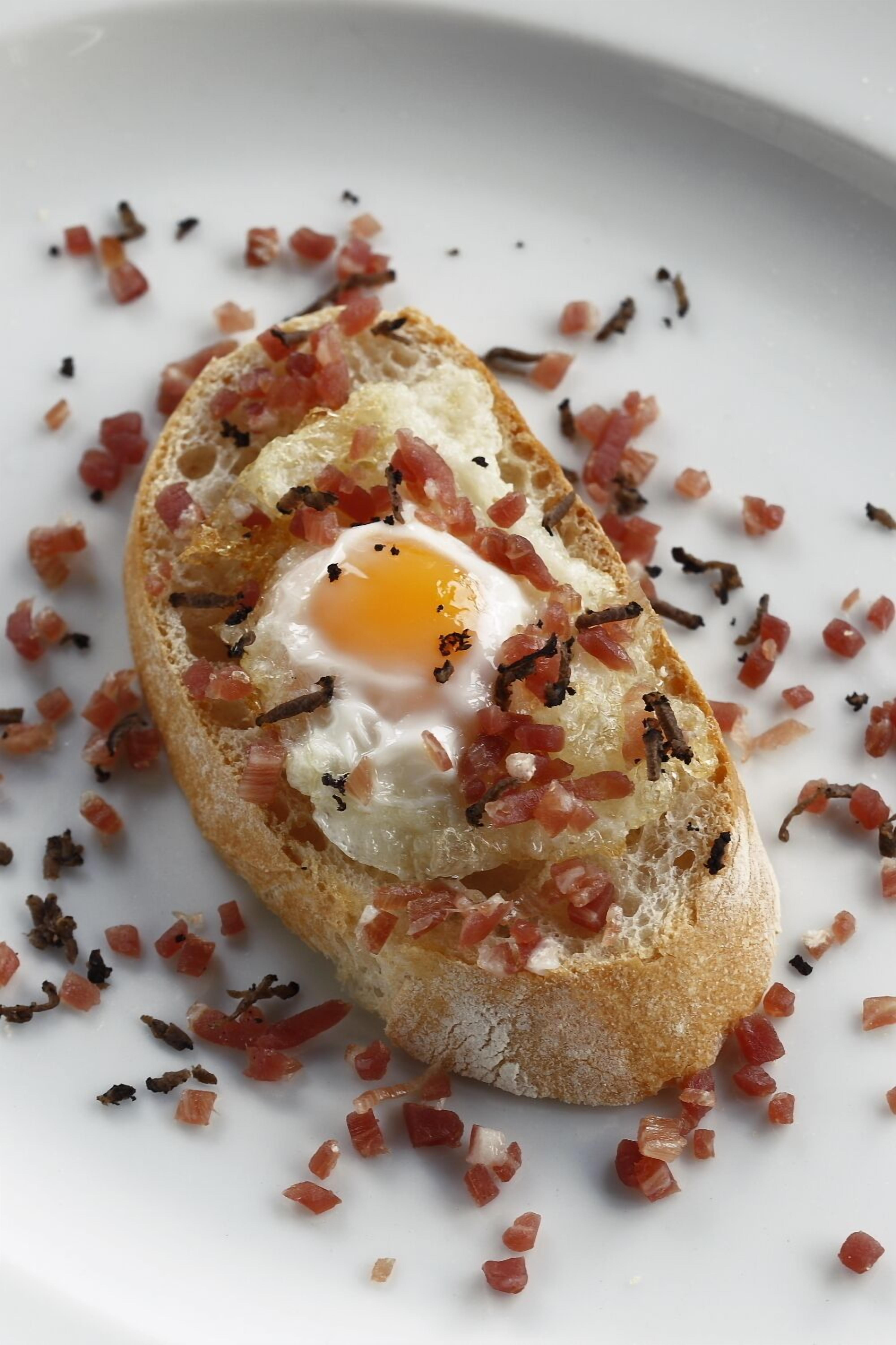 A dish with a fried egg on toast, garnished with diced tomatoes and herbs.