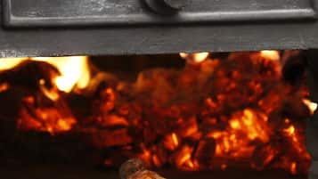 A roasted duck on a plate in front of a wood-fired oven.