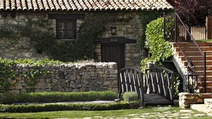 Un edificio de piedra con techo de tejas, puerta de madera y escalera con barandilla de metal.