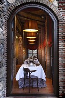 A dining area with a brick wall, a table set for two, and hanging pendant lights.