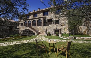 A stone building with a courtyard, a small bridge, and a pond.