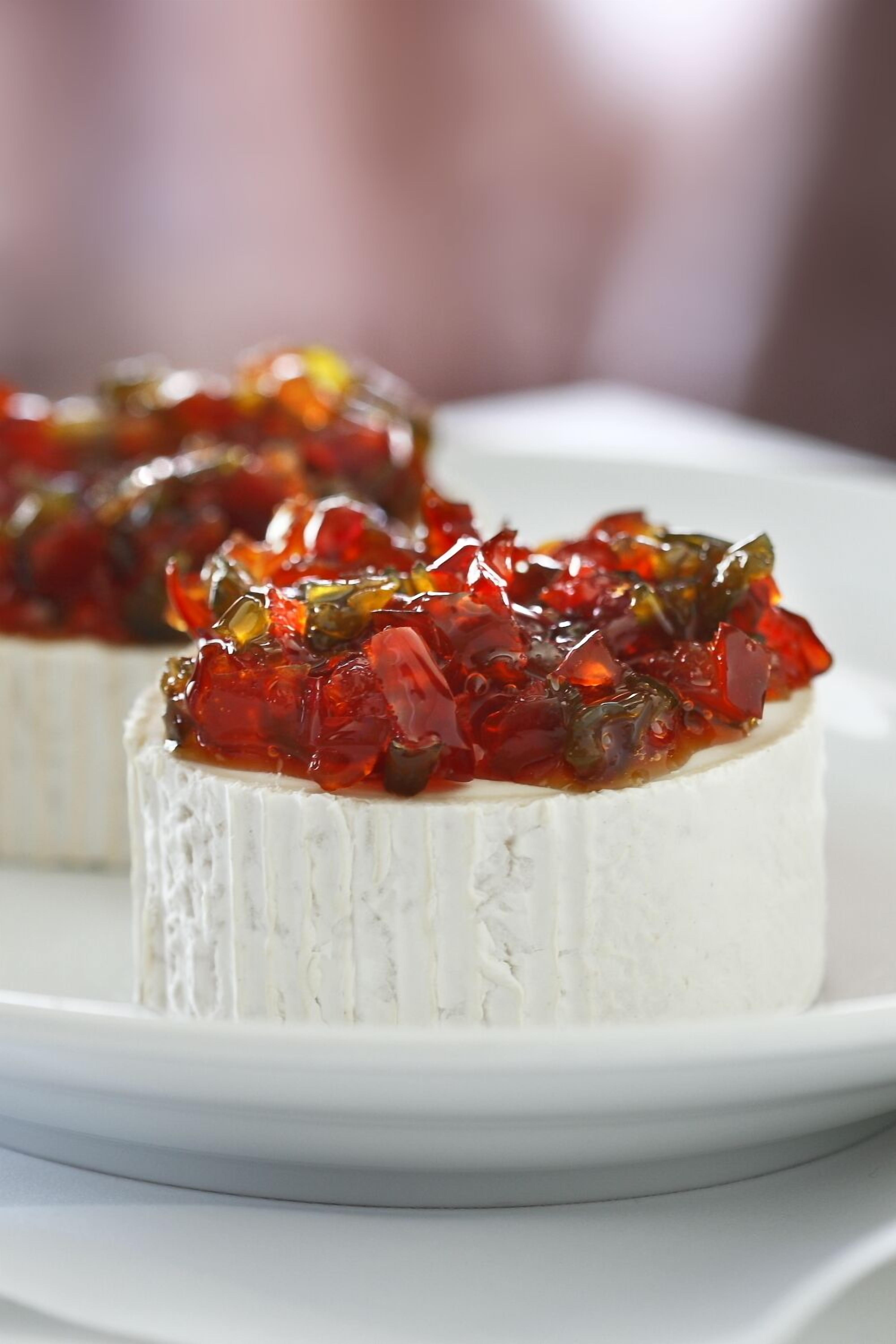A white plate with a white dessert topped with red and green jelly.