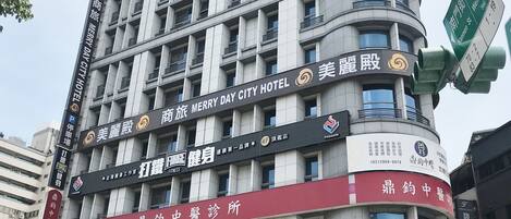 Un immeuble à plusieurs étages, sur lequel on peut voir des enseignes indiquant le « Merry Day City Hotel », un « Japan Medical Center » et une clinique dentaire.