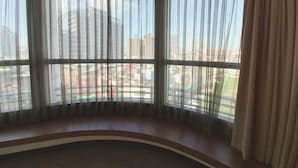 A room with large windows, a curved bench, and a view of a cityscape. - Merryday Hotel Banqiao Branch (New Taipei City)