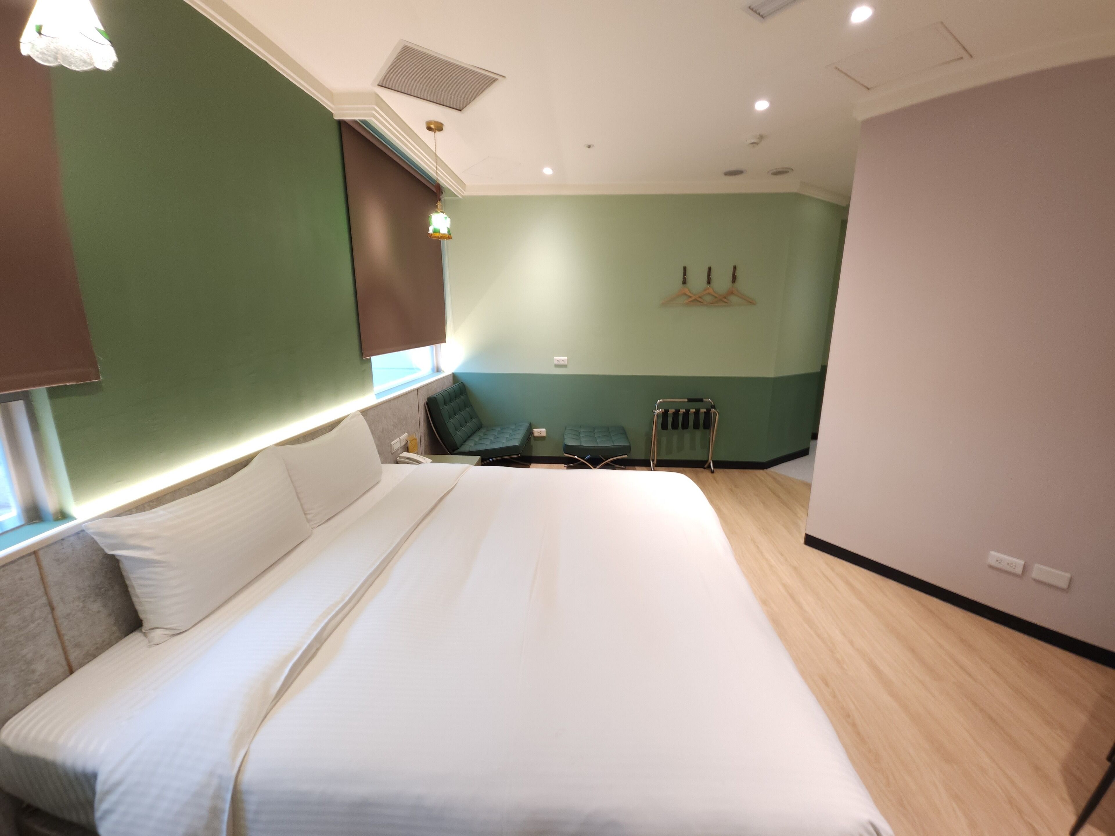 A hotel room with a large bed, a small seating area, and a radiator.