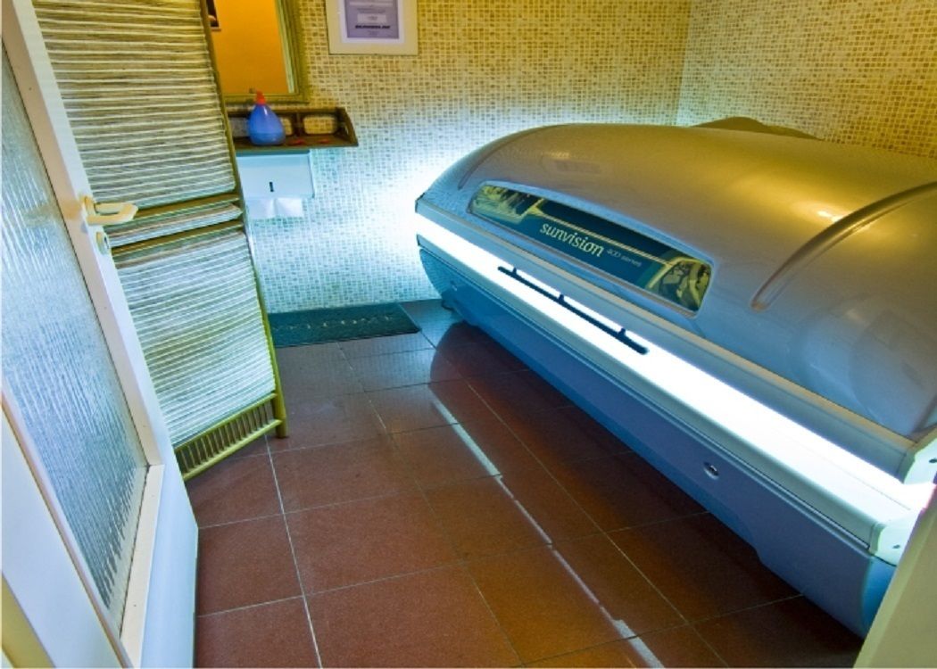 A sauna with a control panel, a towel rack, and a small shelf with items.