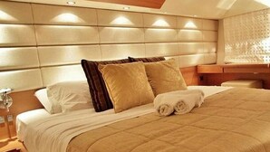 Un lit bien fait, avec une couette beige, deux oreillers et une serviette enroulée.