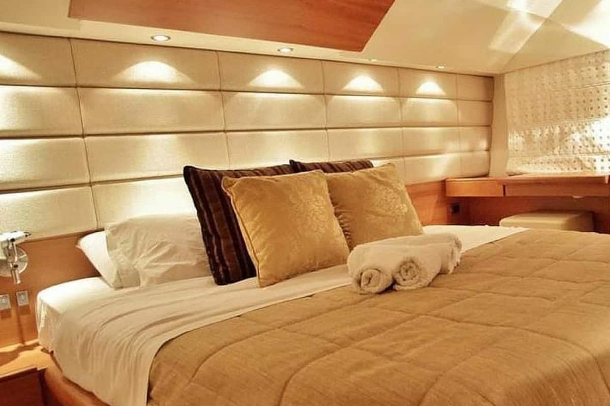 Un lit bien fait, avec une couette beige, deux oreillers et une serviette enroulée.