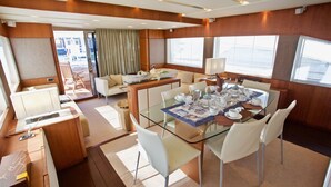 Un espace repas moderne avec une table en verre, des chaises blanches et une vue sur la terrasse extérieure.
