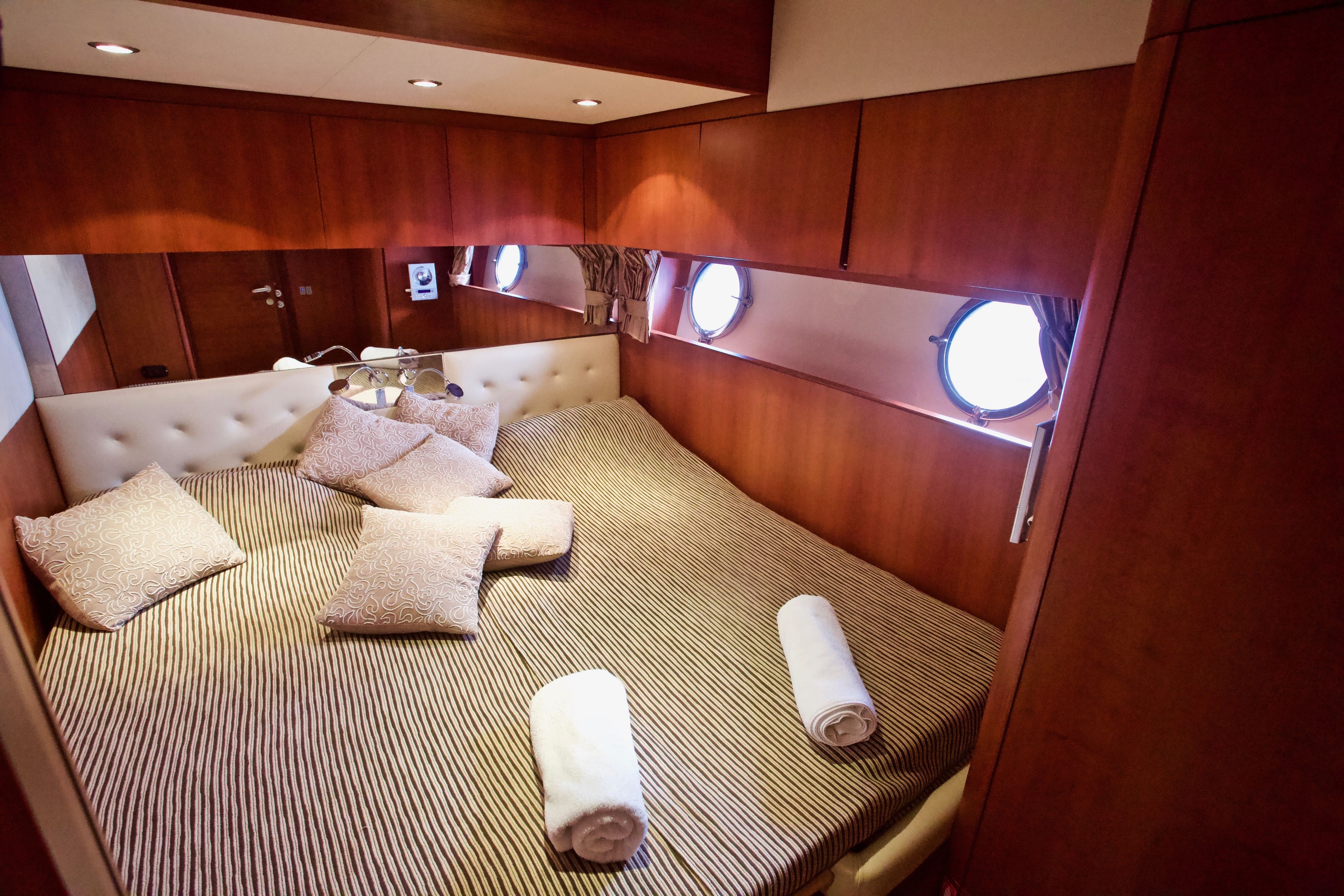 A well-lit, compact bedroom with a striped bedspread, multiple pillows, and a neatly made bed.