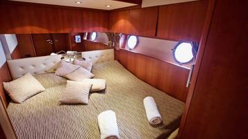 A well-lit, compact bedroom with a striped bedspread, multiple pillows, and a neatly made bed.