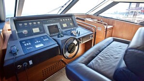 Un poste de pilotage de bateau équipé de plusieurs indicateurs, d’un volant et d’un siège en cuir.