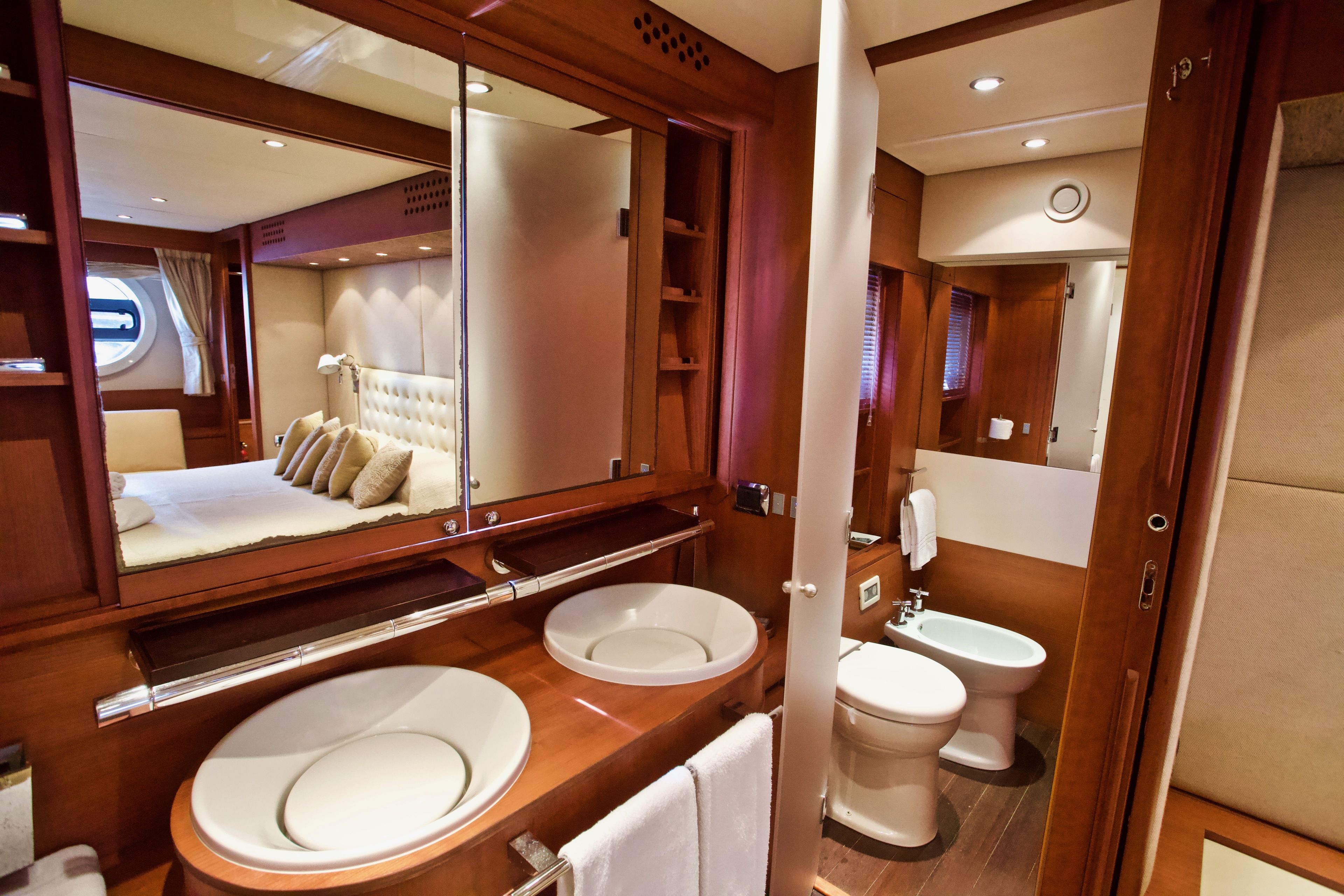 A luxurious bathroom with a large mirror, two sinks, a toilet, and a bidet.