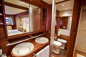 Une salle de bain luxueuse avec un grand miroir, deux lavabos, des toilettes et un bidet.
