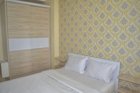 Un dormitorio con una cama, un armario y una mesita de noche.
