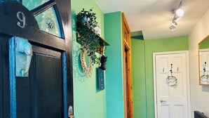 A hallway with a dark blue door marked with the number 9, a green wall, a white door with a wreath, and a radiator. - Pebble Mews Free Parking | By My Getaways (Brighton)
