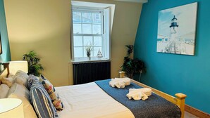 A bedroom with a bed, a window, a radiator, and a painting on the wall. - Pebble Mews Free Parking | By My Getaways (Brighton)