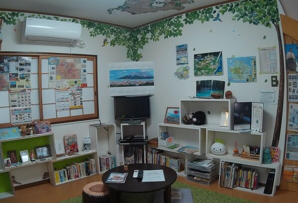 A cozy room with a TV, bookshelves, a bulletin board, and a green carpet.