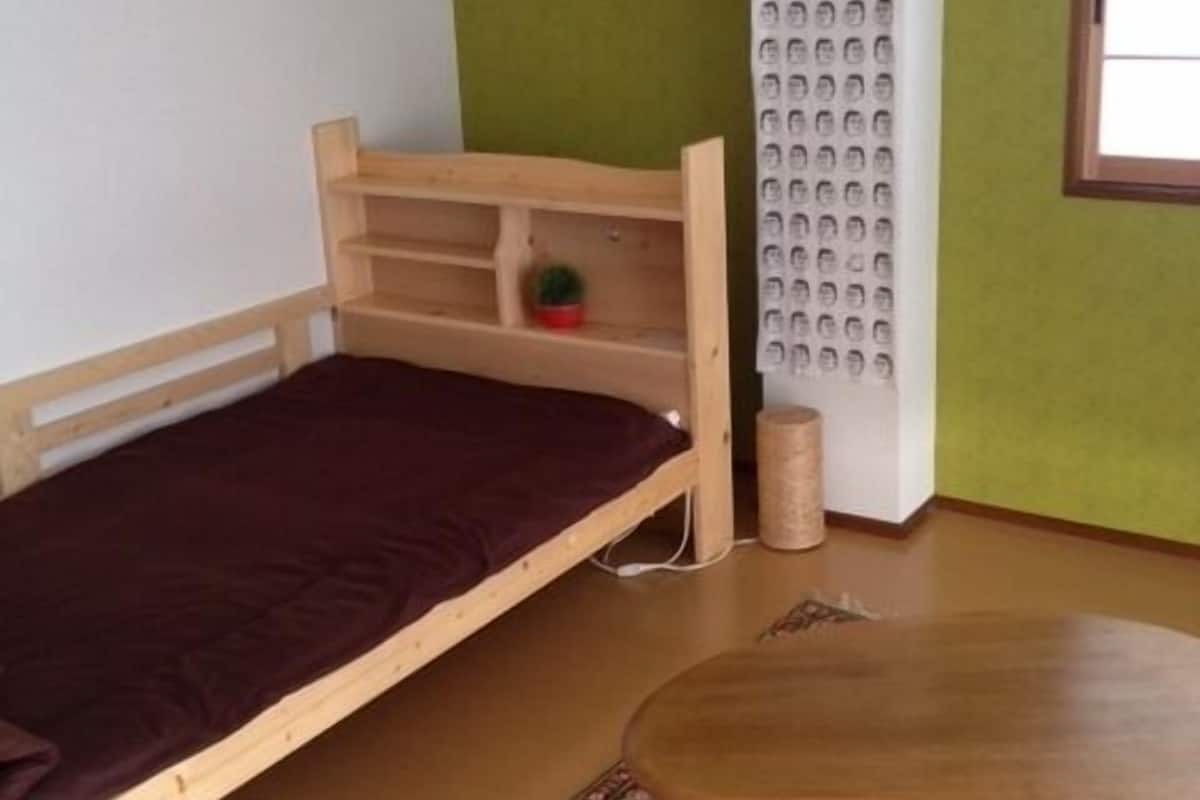 Une petite pièce avec un lit simple, une table ronde et un tapis à motifs.