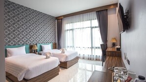 A hotel room with two beds, a TV mounted on the wall, a desk with a lamp, and a large window with curtains. - Eireann Boutique Hotel (Prakhon Chai)