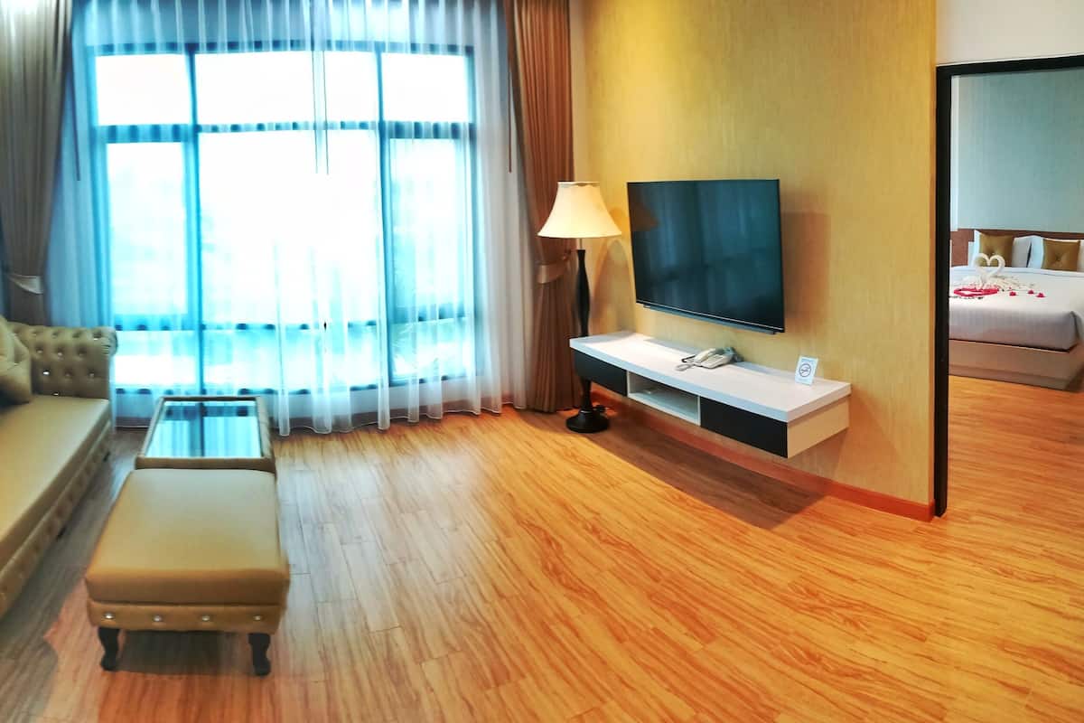 Une chambre d’hôtel avec un canapé, un pouf, une télévision et un lit.
