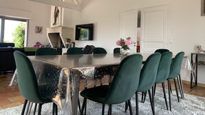 Un comedor con una mesa grande, sillas verdes y un jarrón decorativo.