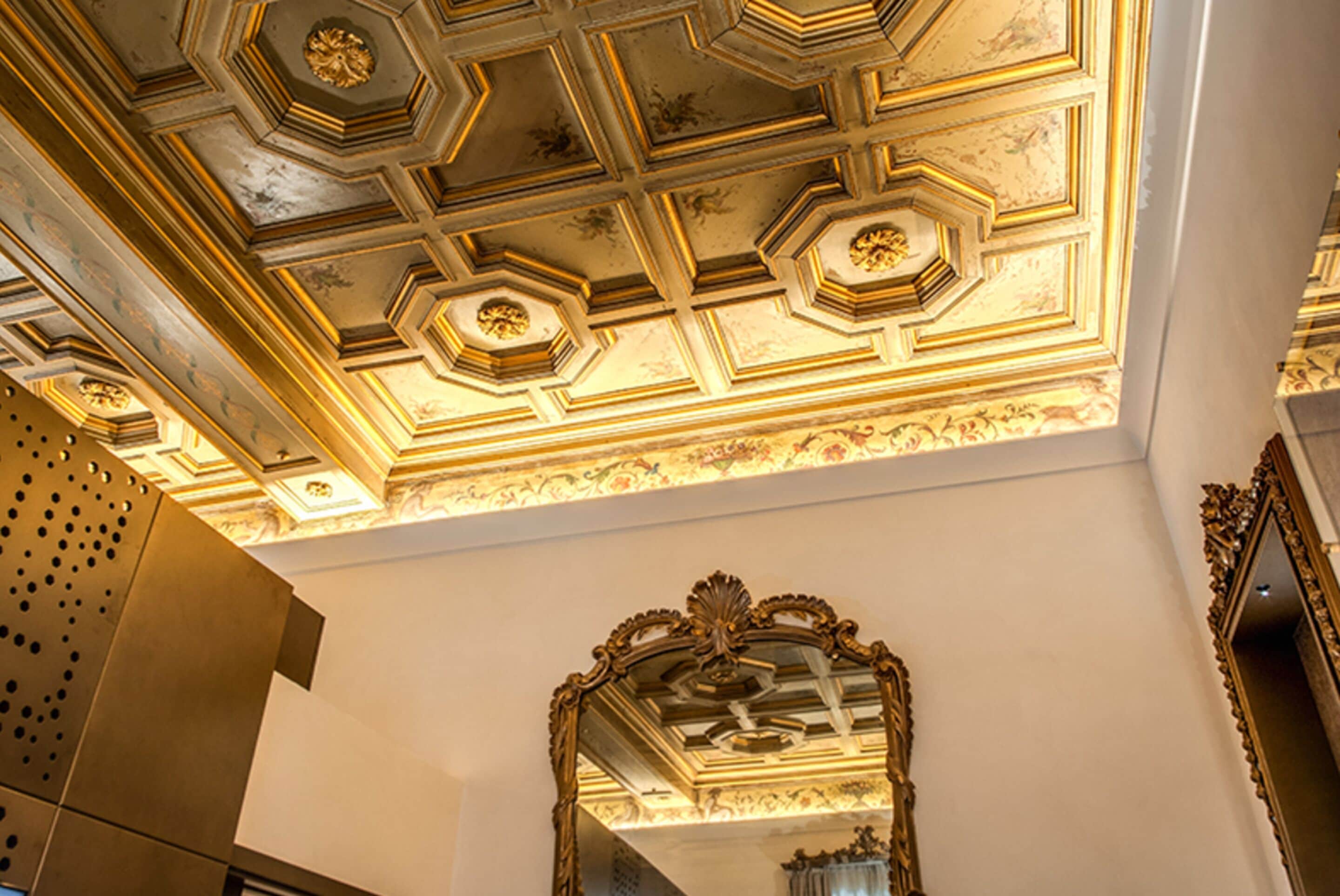 Un techo con intrincados diseños geométricos y un espejo grande y ornamentado.