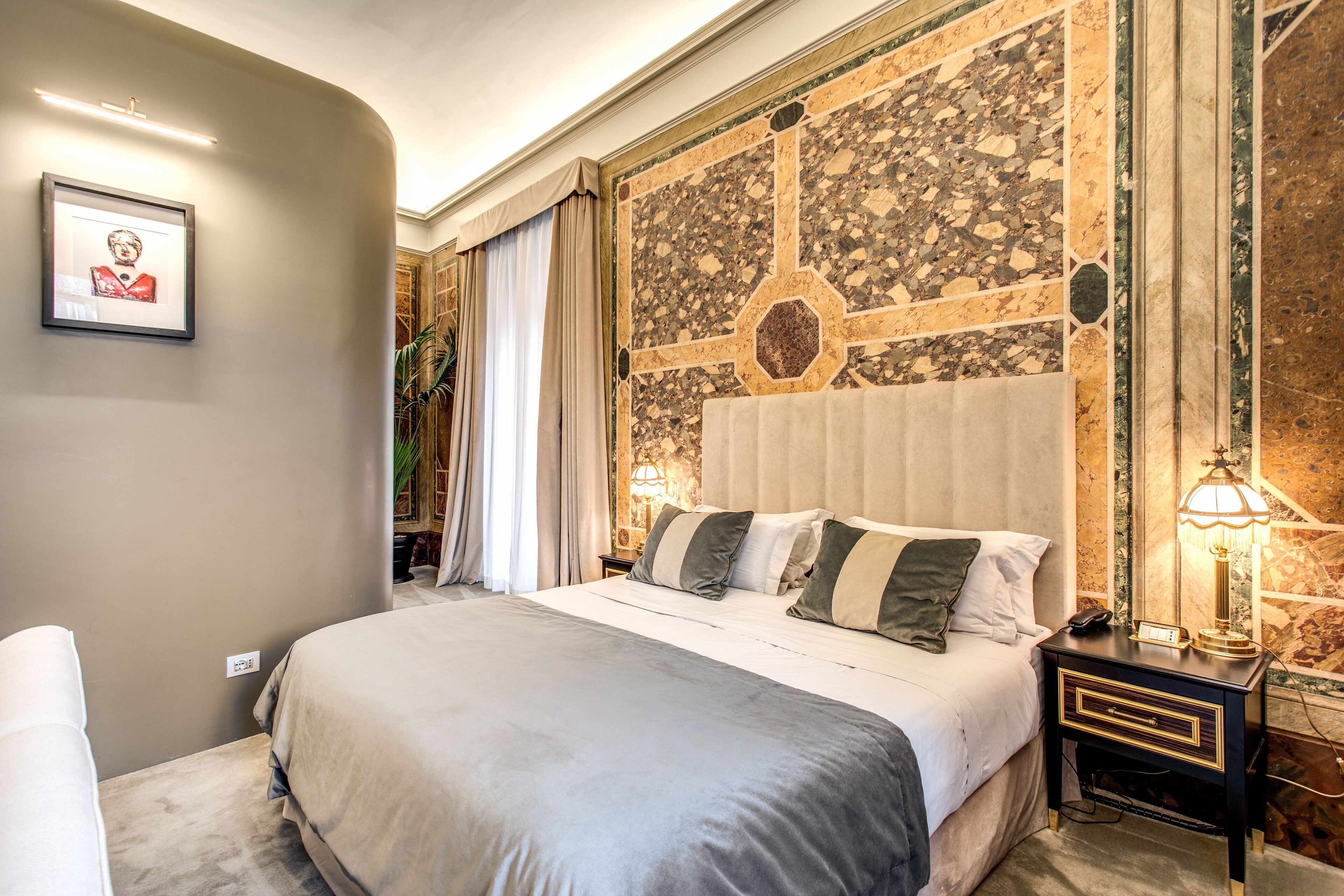 A neatly arranged bedroom with a large bed, a bedside table with a lamp, and a framed picture on the wall.