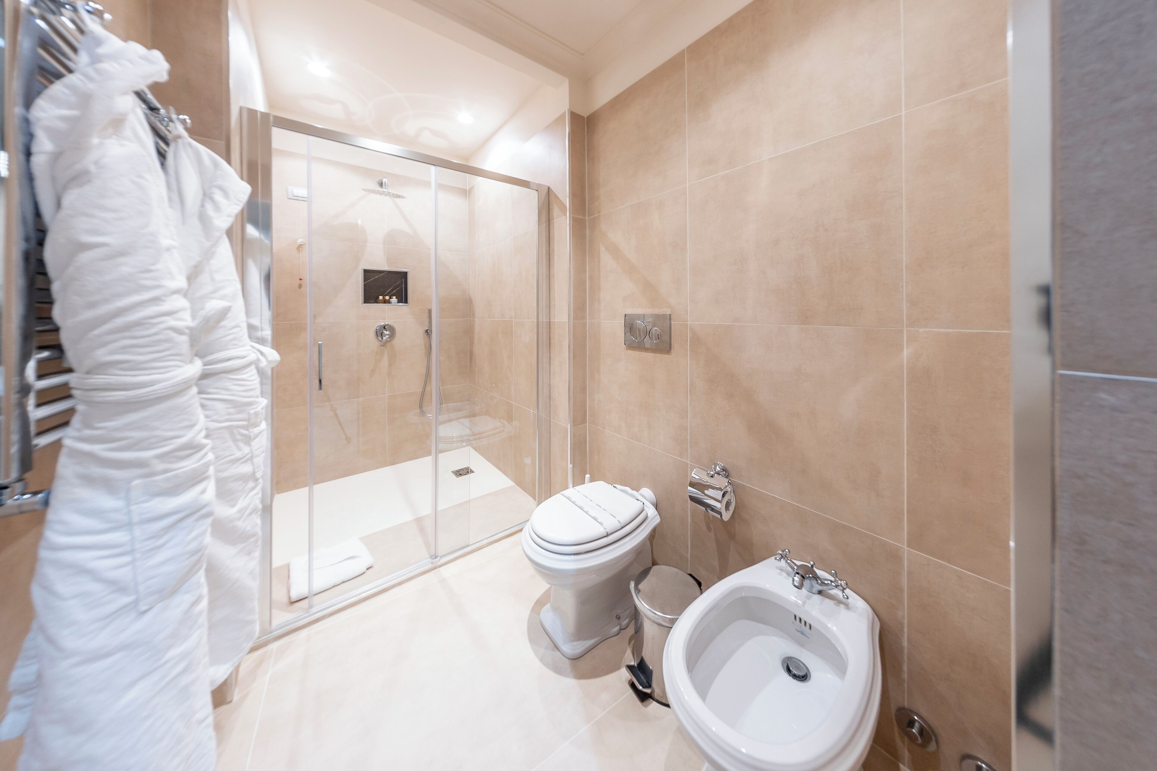 A modern bathroom with a glass shower enclosure, a toilet, and a bidet.