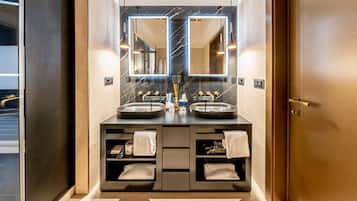 A modern bathroom with dual sinks, a large mirror, and built-in shelves with towels.