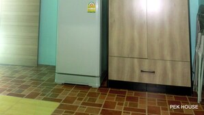 Una habitación con un refrigerador blanco, un armario de madera y un aire acondicionado en la pared.