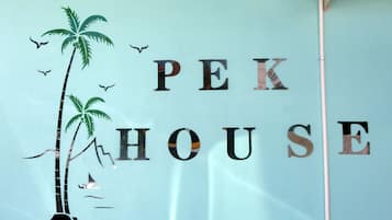 A wall with the text "PEK HOUSE" and decorative elements including palm trees and birds.