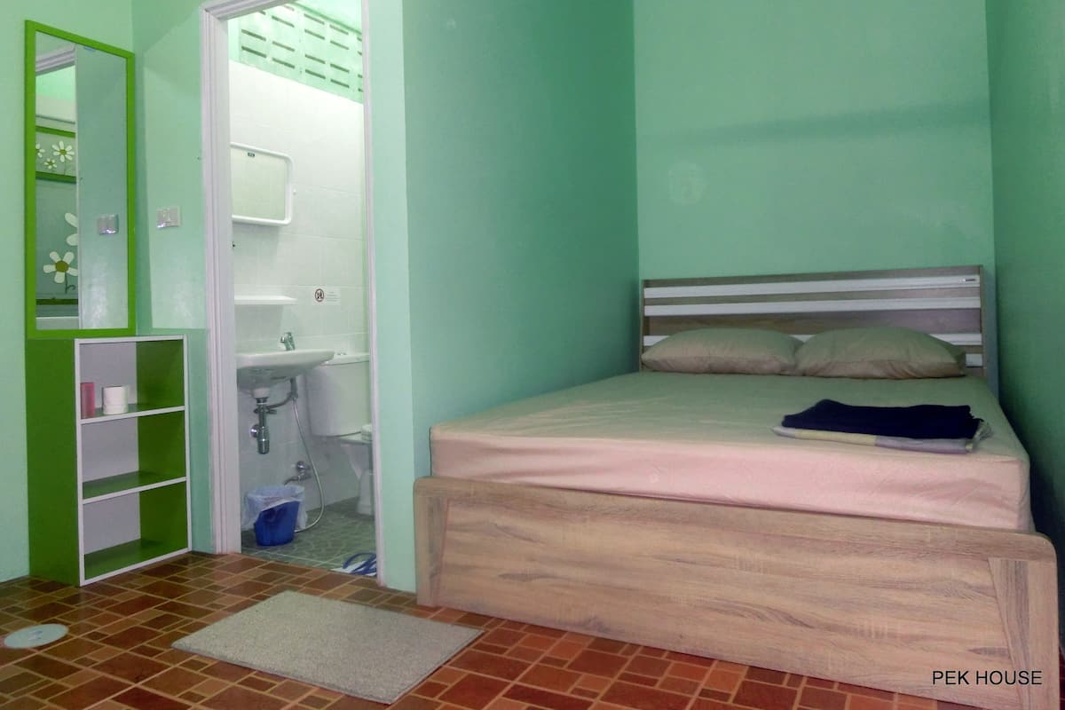 Une chambre à coucher avec un lit, une petite salle de bain et un mur vert.