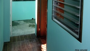 Un pasillo estrecho con una puerta de madera y un ventanal con barrotes.