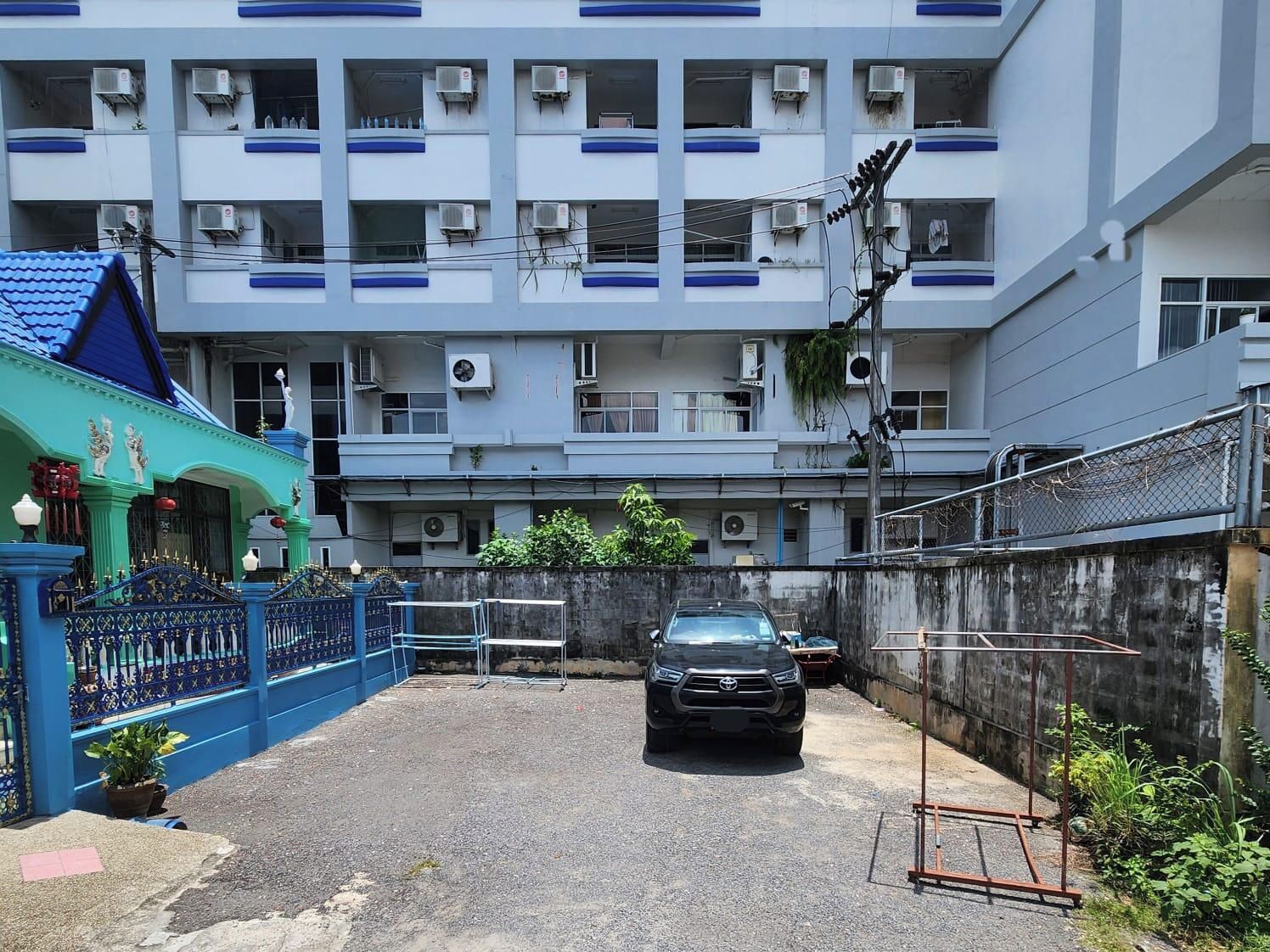 A multi-story residential building with balconies, air conditioning units, and a gated entrance.