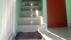 Una escalera con una puerta roja al final, que lleva a una habitación con paredes verdes.