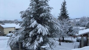 A snow-covered residential area with houses and a large evergreen tree. - Artesano III (Navarredonda de Gredos)