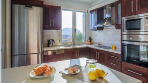 Una cucina moderna con elettrodomestici in acciaio inossidabile, pensili in legno e un'ampia finestra che offre vista sull'esterno.